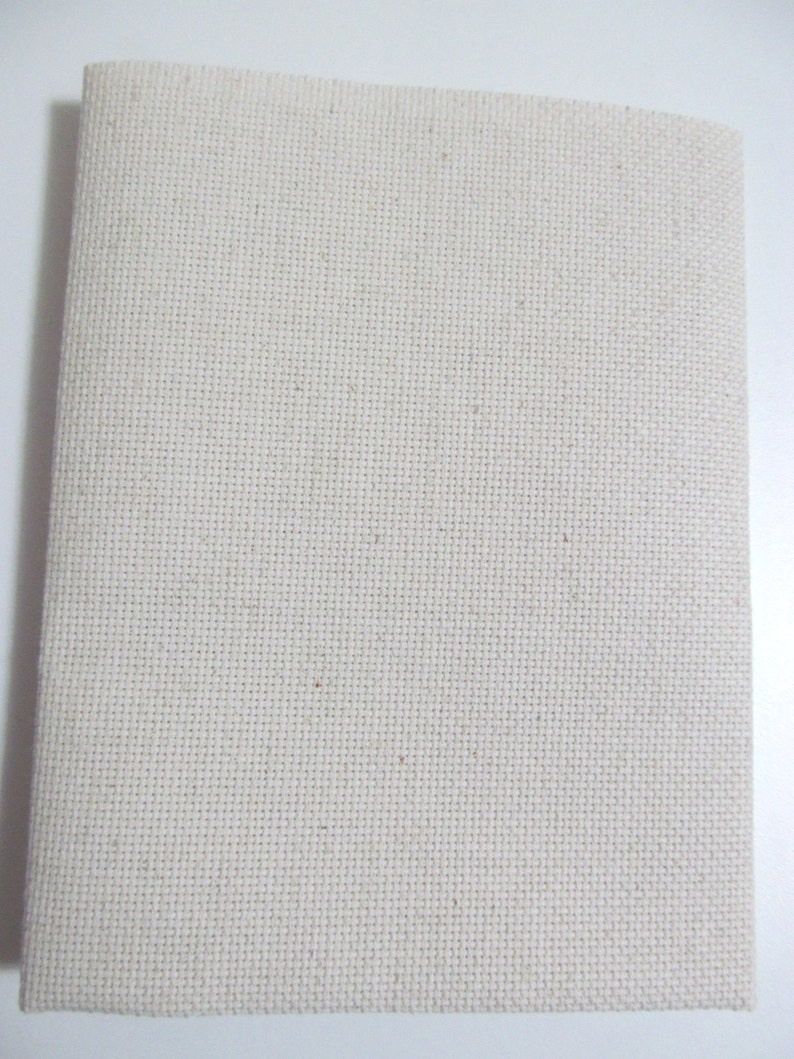 May include: A rectangular piece of off-white cross-stitch fabric, folded in half. The fabric has a visible grid pattern, ideal for embroidery or cross-stitch projects. The material appears to be a natural fiber, possibly cotton or linen.