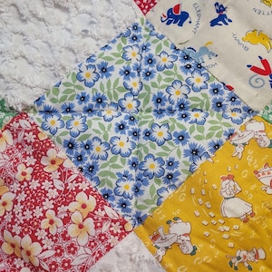 May include: A patchwork quilt with a variety of colorful fabrics. The quilt features a blue and white floral pattern, a red and white floral pattern, a yellow and white pattern with a girl playing cards, and a white fabric with a textured surface. The quilt is made with squares of fabric sewn together.