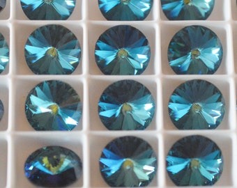 May include: A close-up view of a tray of teal blue round rhinestones. The rhinestones are arranged in a grid pattern and are all the same size.