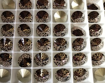 May include: A tray of 25 round, faceted rhinestones with a leopard print design. The rhinestones are arranged in a grid pattern and are a mix of gold and brown colors.