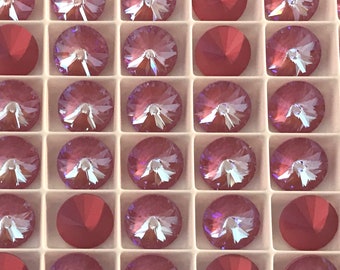 May include: A close-up view of a tray of pink and red rhinestones. The rhinestones are arranged in a grid pattern and are all the same size. The rhinestones are shiny and have a faceted surface.