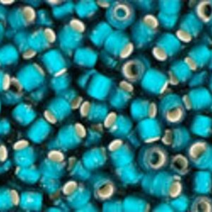 May include: A close-up image of a large quantity of teal blue glass beads with white centers. The beads are small and round, and they are arranged in a random pattern.