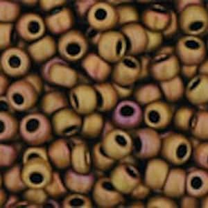 May include: Close-up of a pile of small, round beads. The beads are primarily a muted gold color with a hint of pink and a black center. These beads are suitable for jewelry making and crafting.