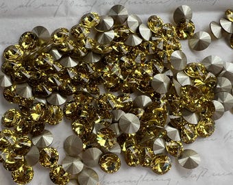 May include: A collection of faceted, round-cut rhinestones in shades of gold and silver. The gold rhinestones have a warm, amber hue, while the silver ones have a metallic, matte finish. These decorative embellishments are ideal for crafts and jewelry making.