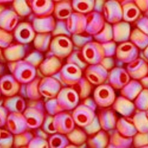 May include: A close-up of a pile of small, round, pink and white beads with a red center. The beads are made of glass and have a shiny finish.