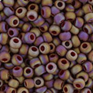 May include: A large pile of small, round, iridescent glass beads. The beads are a mix of light purple, brown, and beige colors with a red center hole.