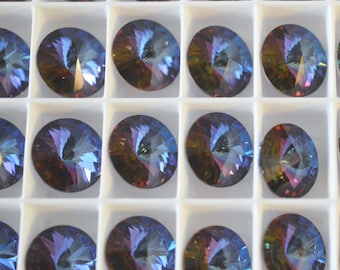 May include: A close-up view of a white tray filled with round, iridescent, multi-colored glass rhinestones. The rhinestones are arranged in rows and columns, creating a symmetrical pattern.