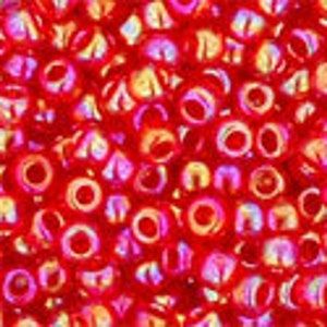 May include: A close-up of a large quantity of small, red, iridescent glass beads. The beads are round with a hole in the center and have a slightly metallic sheen.