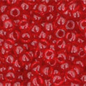 May include: A close-up image of a large quantity of small, red, round beads. The beads are shiny and have a slight iridescent quality.