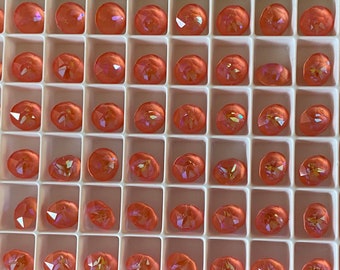 May include: A close-up view of a tray of 49 round, iridescent, peach-colored glass beads. The beads are arranged in a grid pattern in a white tray.
