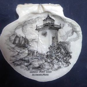 May include: A black and white illustration of Grindal Point Light, Islesboro, Maine, on a white seashell. The lighthouse is depicted with a tall tower and a small house next to it. A sailboat is in the background.