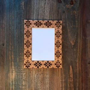 May include: A wooden picture frame with a geometric pattern in brown and black. The frame is empty and ready for a photo.