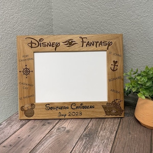 May include: Wooden picture frame with the words "Disney Fantasy" engraved at the top. The frame includes engraved text and images of a compass, anchor, and ship, with the words "Southern Caribbean July 2023".