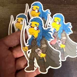 May include: A die-cut sticker featuring a yellow-skinned cartoon character with long blue hair, wearing round red glasses, a dark gray hooded cloak, and brown boots. The character holds a wooden bow and carries a small white creature in one arm.