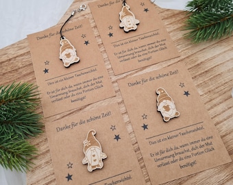 May include: Four brown paper cards with a small wooden gnome keychain attached to each. The cards have the text "Danke für die schöne Zeit!" and "Dies ist ein kleiner Taschenwichtel. Er ist für dich da, wann immer du eine Umarmung brauchst, dich der Mut verlässt oder du eine Portion Glück benötigst!" printed on them.