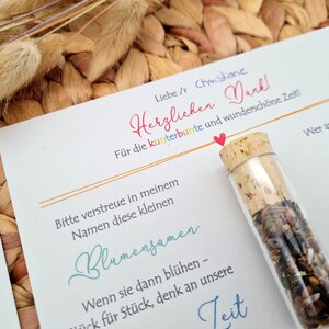 K&ouml;nnte beinhalten: Eine wei&szlig;e Karte mit einer handschriftlichen Nachricht auf Deutsch, die sich f&uuml;r die Zeit bedankt. Die Karte ist mit einem kleinen Glasfl&auml;schchen gef&uuml;llt mit Blumensamen, einem Regenbogen und einem Herzen verziert.