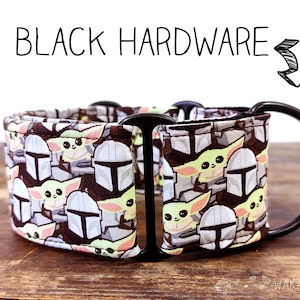 Puede incluir: Un collar de perro con estampado en blanco y negro con herrajes negros. El estampado presenta una imagen repetida de una pequeña criatura verde y blanca con orejas grandes. El collar está hecho de tela y tiene una hebilla de metal.