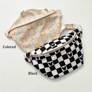 May include: Two fanny packs with gold zippers and adjustable straps. One is a pastel checkered pattern with Mickey Mouse silhouettes. The other is a black and white checkered pattern with Mickey Mouse silhouettes. The word "Colored" is printed on the left side of the pastel fanny pack. The word "Black" is printed on the left side of the black fanny pack.