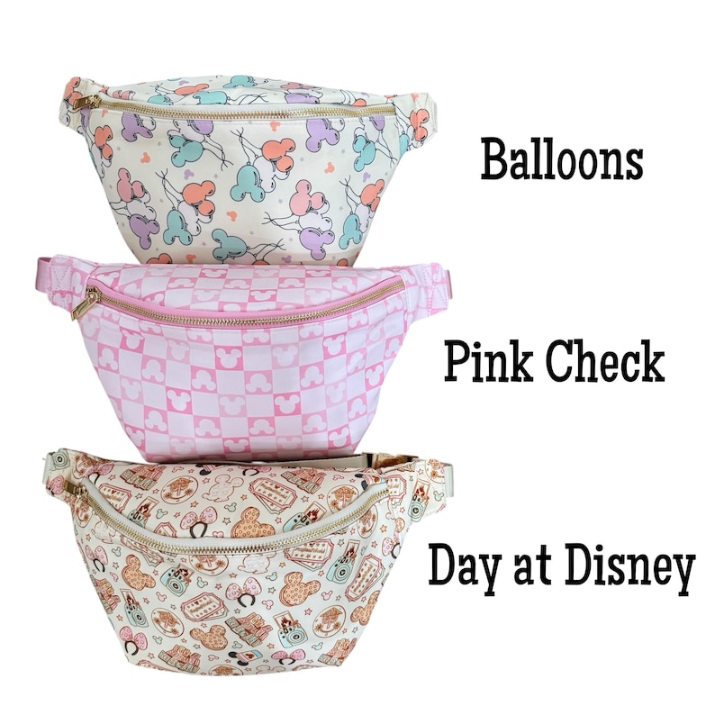 May include: Three fanny packs with different patterns. The top one is cream-colored with a balloon and Mickey Mouse head print. The middle one is pink with a pink and white checkerboard pattern. The bottom one is cream-colored with a Disney-themed print.