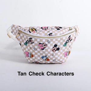 May include: Tan and white checkered fanny pack featuring cartoon characters. The bag has a gold zipper and a white strap. The text "Tan Check Characters" is printed on the bottom.