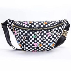 May include: Black and white checkered fanny pack with a gold zipper and black strap. The bag is decorated with colorful cartoon character graphics. The fanny pack is a stylish accessory for carrying essentials.