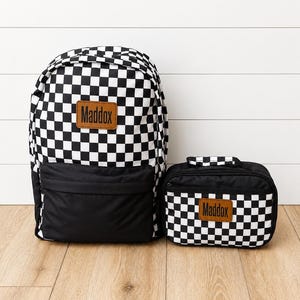 Mochila e lancheira infantis personalizadas, com detalhe em couro xadrez preto, para a volta às aulas.