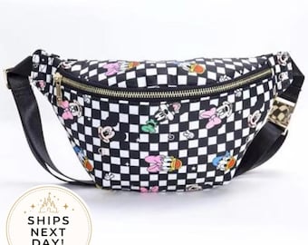 May include: A black and white checkered fanny pack featuring a repeating pattern of colorful cartoon characters including mice and ducks. The bag has a gold-toned zipper closure across the top and an adjustable black strap with a metallic buckle component.