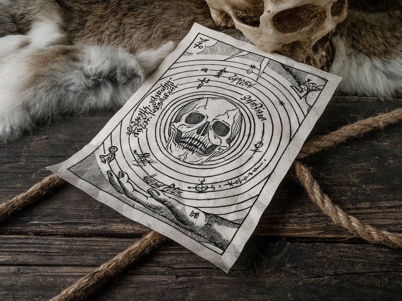 K&ouml;nnte beinhalten: Ein Pergamentpapier im Vintage-Stil mit einem Totenkopf- und Knochenkreuz-Design. Das Pergament ist von einem Kreis aus Text und Symbolen umgeben. Das Pergament liegt auf einer Holzoberfl&auml;che.