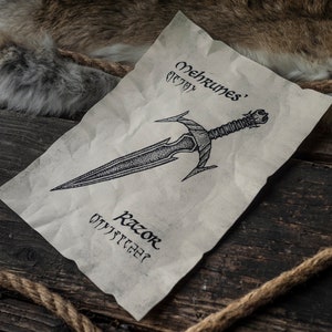May include: A black and white illustration of a dagger on a piece of parchment paper. The dagger is labeled "Mehrunes' Razor" in a stylized font.
