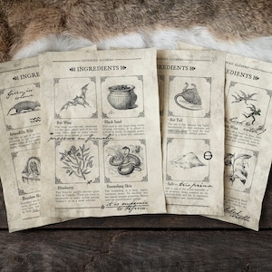 Op de afbeelding: Close-up van vijf vintage-stijl papieren kaarten met zwart-wit illustraties van verschillende ingrediënten. De kaarten zijn gelabeld "Advanced Alchemy" en bevatten ingrediënten zoals "Bat Wing", "Black Sand", "Rat Tail", "Boomslang Skin" en "Salt-tris prima".