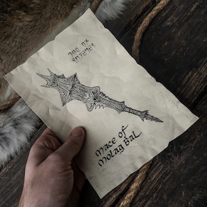 May include: A hand holds a piece of parchment paper with a drawing of a sword and the text "Mace of Molag Bal".