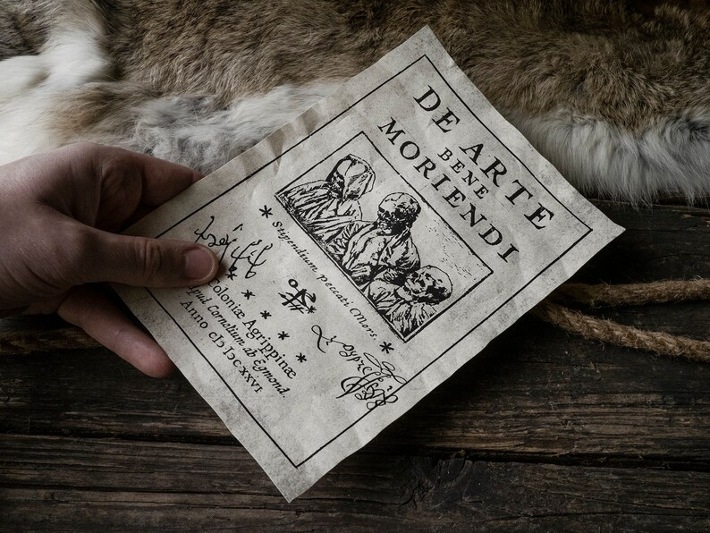 K&ouml;nnte beinhalten: Ein altes, gealtertes Papierdokument mit dem Titel "De Arte Bene Moriendi" und einer Holzschnitt-Illustration von drei Figuren in Kapuzenroben. Der Text unter dem Bild lautet "Stipendium Peccati Mors" und "Coloni&aelig; Agrippin&aelig; Apud Cornelium ab Egmond. Anno clo loc XXVI."