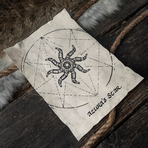 May include: A black and white illustration of a star with eight points, surrounded by a circle and a geometric pattern. The paper is aged and has a brown tint. The text "Azura's Star" is written in cursive at the bottom of the paper.