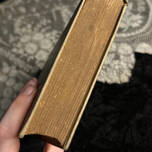 Peut inclure: Un livre vintage avec des pages jaunies et une couverture claire et us&eacute;e. Les bords du livre sont l&eacute;g&egrave;rement arrondis, montrant des signes d'&acirc;ge et d'utilisation. Le dos est d'une couleur plus claire que les pages.