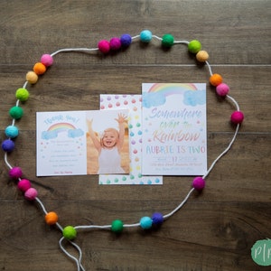 Puede incluir: Un juego de invitaciones de cumplea&ntilde;os con tem&aacute;tica de arco&iacute;ris. El juego incluye una tarjeta con una foto de un ni&ntilde;o, una tarjeta de agradecimiento y una invitaci&oacute;n que dice "Somewhere over the Rainbow, Aubrie is Two". Una guirnalda de bolas de fieltro coloridas rodea las tarjetas.