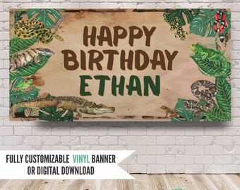 May include: A rectangular banner featuring the text HAPPY BIRTHDAY ETHAN in brown and green letters. The design includes illustrations of various reptiles and amphibians, including a crocodile, snakes, lizards, and a frog, surrounded by green tropical leaves.