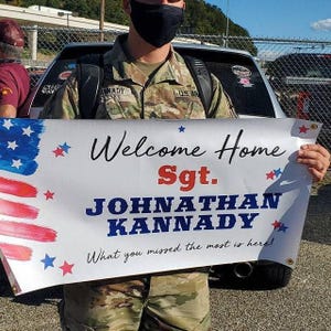 Personalized “Welcome Home Sgt.” vinyl banner held in front of a car for military homecoming celebration.