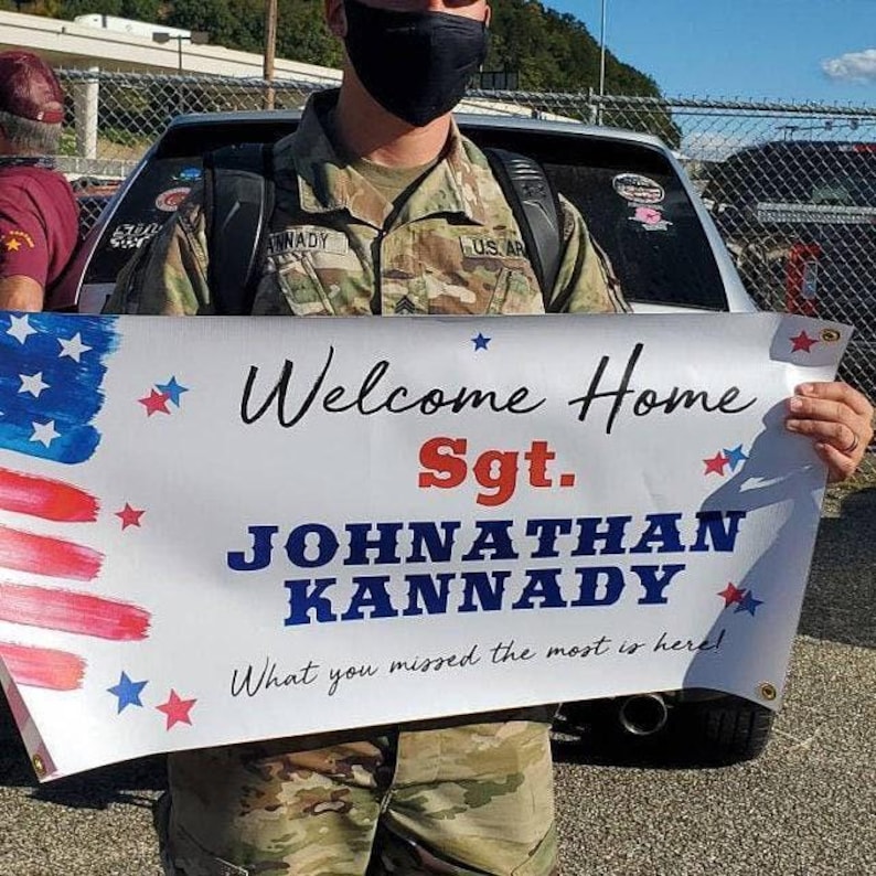 Personalized “Welcome Home Sgt.” vinyl banner held in front of a car for military homecoming celebration.