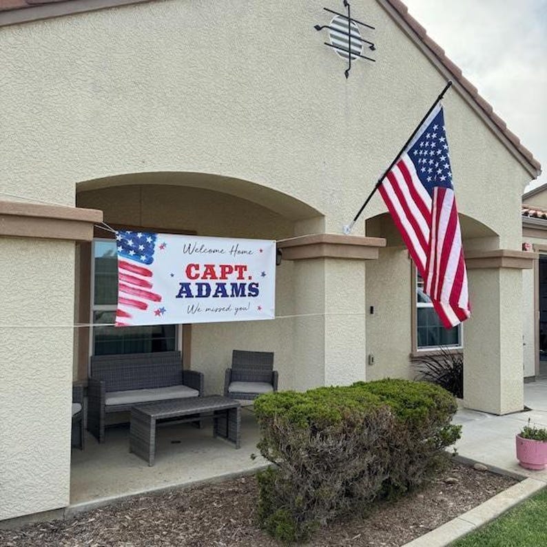 Patriotic “Welcome Home Soldier” banner displayed near entryway for military homecoming celebration with American Flag.