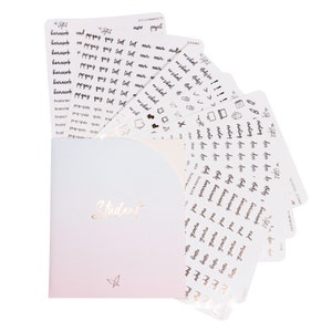 May include: A set of student planner stickers with gold lettering on white sheets. The stickers include words like "homework", "test", "quiz", "reading", "study", and "research". The stickers are arranged in a fan shape and are partially visible in a folder with a gradient background.