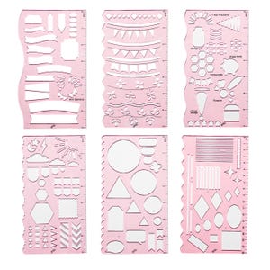 May include: Six pink plastic stencils with various shapes and designs for journaling and crafting. Each stencil features different shapes, including banners, circles, and geometric figures, with inch measurements along the edges.
