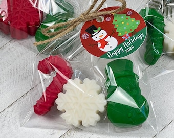 May include: A clear plastic bag filled with small Christmas-themed soaps. The soaps are shaped like a candy cane, snowflake, snowman, and Christmas tree. The bag has a brown twine bow and a round tag that says "Happy Holidays 2022" with a snowman and Christmas tree illustration.