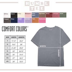 Op de afbeelding: Een grijs Comfort Colors t-shirt met afmetingen voor maat, breedte en lengte. De afbeelding bevat een kleurenkaart met opties zoals wit, zwart en blue jean. De tekst "HUMBLE TEE" staat bovenaan.