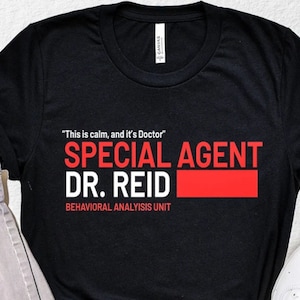 May include: Black t-shirt with white text that reads "This is calm, and it's Doctor" "SPECIAL AGENT DR. REID" "BEHAVIORAL ANALYSIS UNIT".