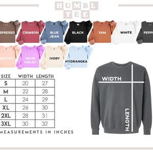 Peut inclure: Un sweat-shirt gris avec un tableau des tailles et des options de couleurs. Le tableau indique les mesures en pouces, les tailles allant de S &agrave; 3XL. Les options de couleurs incluent Espresso, Crimson, Blue Jean, Black, Yam, White, Pepper, Peachy, Neon Violet, et Hydrangea.