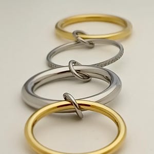 Peut inclure: Quatre anneaux entrelacés, deux en or et deux en argent, dont un anneau orné d'une rangée de petits diamants.