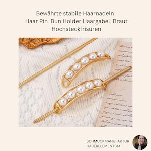 Pode incluir: Dois grampos de cabelo dourados com detalhes de pérolas. Os grampos são curvos e têm uma fileira de pérolas na parte superior. Os grampos estão sobre um fundo branco.