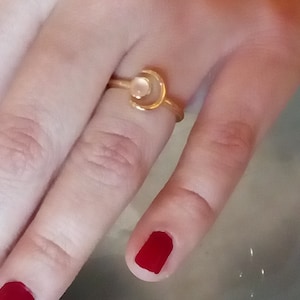 May include: A gold ring with a crescent moon design and a white stone in the center.