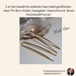 Op de afbeelding: Twee goudkleurige haarspelden, ook wel haarvorken genoemd, worden gepresenteerd op een witte schelp. De tekst "Must Have" is geschreven in zwarte inkt op een witte achtergrond. De tekst "SCHMUCKMANUFAKTUR HABERELEMENTS14" is geschreven in zwarte tekst op een witte achtergrond.