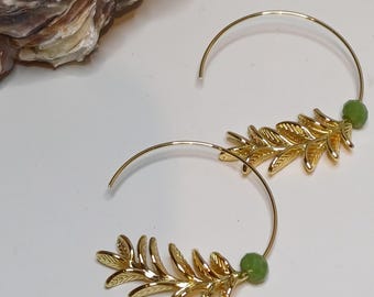 Pode incluir: Brincos de argola dourados com um delicado design de folhas douradas e um detalhe de pedra preciosa verde.